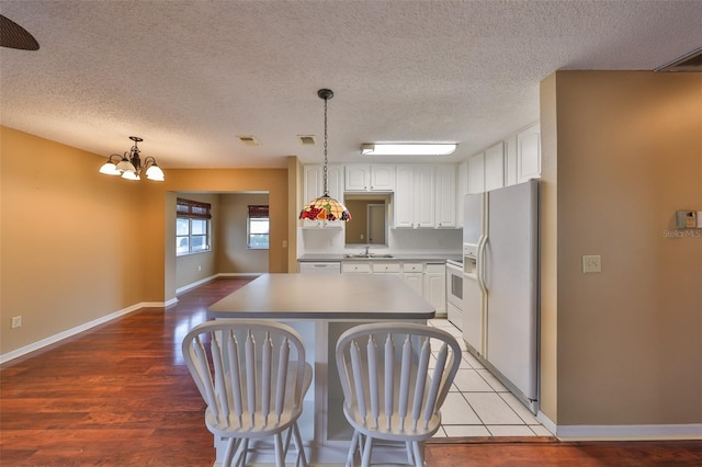 kitchen with decorative light fixtures, a center island, light hardwood / wood-style flooring, white appliances, and white cabinets