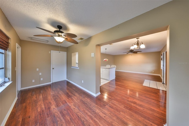 unfurnished room with dark hardwood / wood-style floors, ceiling fan with notable chandelier, and a textured ceiling