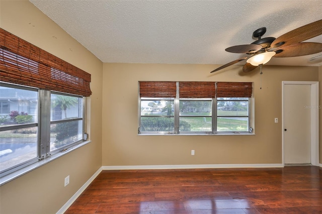 empty room with ceiling fan, a healthy amount of sunlight, dark hardwood / wood-style flooring, and a textured ceiling