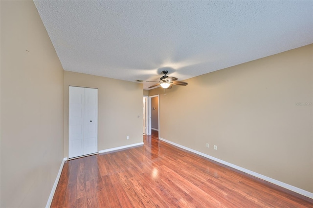 unfurnished room featuring hardwood / wood-style flooring, ceiling fan, and a textured ceiling