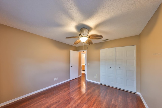 unfurnished bedroom featuring a closet, a textured ceiling, dark hardwood / wood-style floors, and ceiling fan