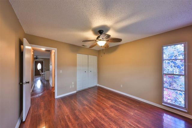 unfurnished bedroom featuring dark hardwood / wood-style floors, a textured ceiling, ceiling fan, and a closet