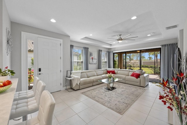 tiled living room featuring a textured ceiling, a raised ceiling, and ceiling fan