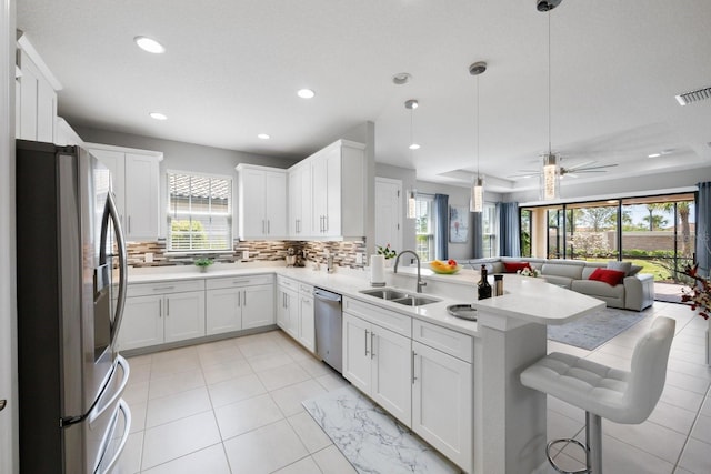 kitchen featuring pendant lighting, stainless steel appliances, sink, and white cabinets