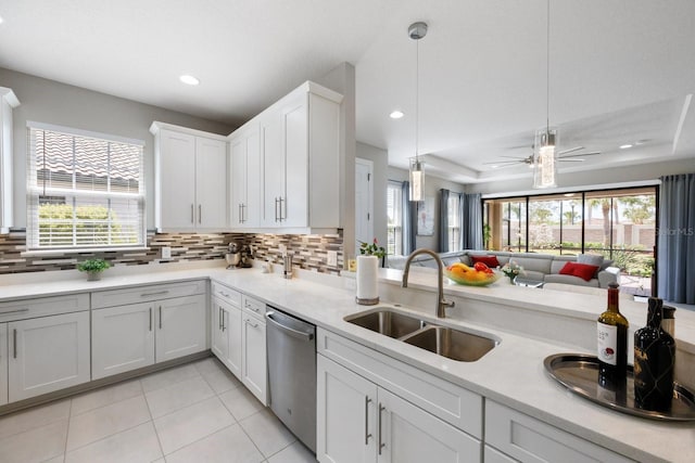 kitchen featuring pendant lighting, sink, white cabinetry, tasteful backsplash, and stainless steel dishwasher