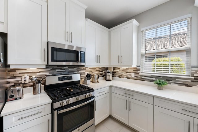 kitchen featuring white cabinetry, stainless steel appliances, light tile patterned flooring, and backsplash