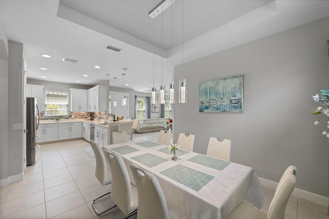 tiled dining space featuring a raised ceiling and sink