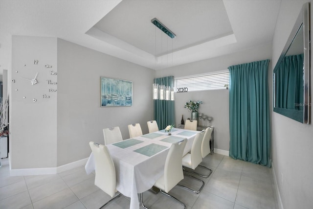 dining space with a raised ceiling and light tile patterned floors