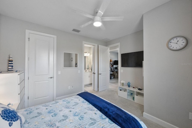 bedroom featuring light colored carpet, ceiling fan, and ensuite bathroom