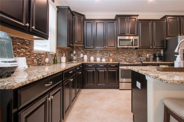 kitchen featuring tasteful backsplash, dark brown cabinets, ornamental molding, appliances with stainless steel finishes, and light stone countertops