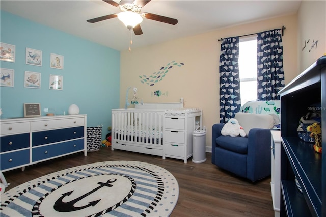 bedroom with a crib, ceiling fan, and dark hardwood / wood-style flooring