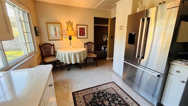 kitchen with white cabinetry, high quality fridge, light tile patterned floors, and a wealth of natural light