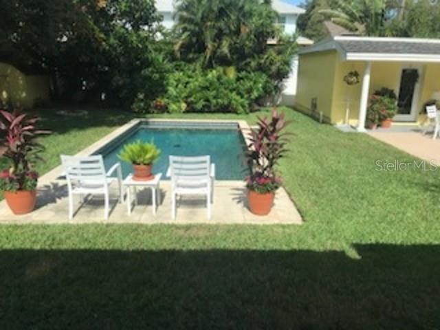 view of pool with a yard, an outbuilding, and a patio area