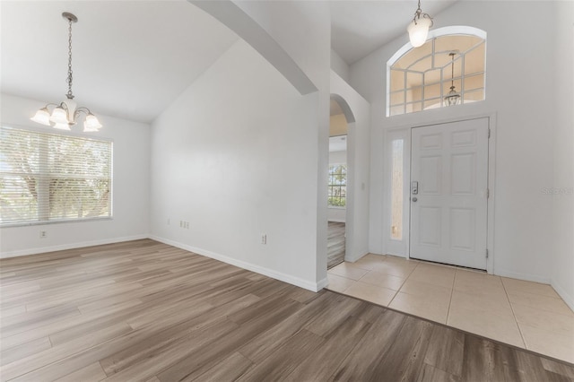 entryway with vaulted ceiling, an inviting chandelier, and light wood-type flooring