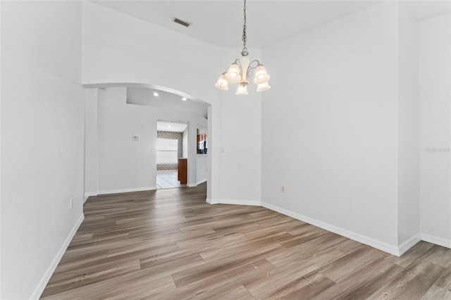 unfurnished dining area featuring a chandelier and hardwood / wood-style floors