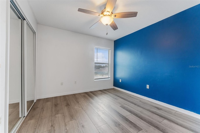 unfurnished bedroom with light hardwood / wood-style flooring, a closet, and ceiling fan