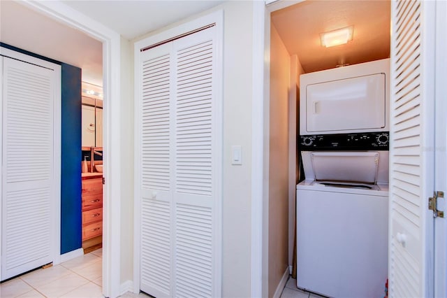 laundry room featuring stacked washer / dryer and light tile patterned floors