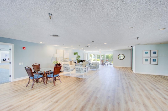 dining space with a textured ceiling and light wood-type flooring