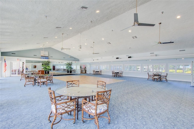 dining area with ceiling fan, high vaulted ceiling, carpet floors, and a textured ceiling