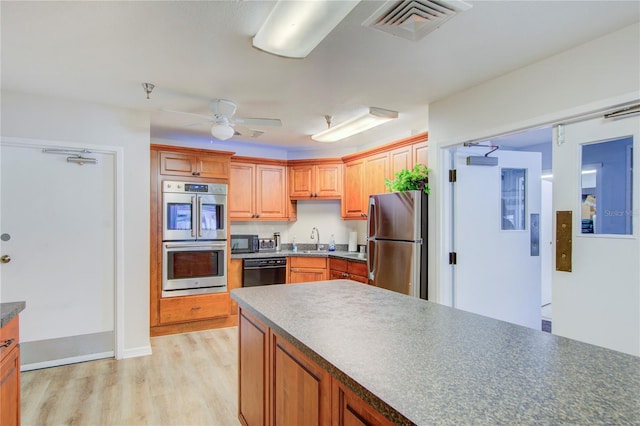 kitchen featuring ceiling fan, appliances with stainless steel finishes, sink, and light wood-type flooring