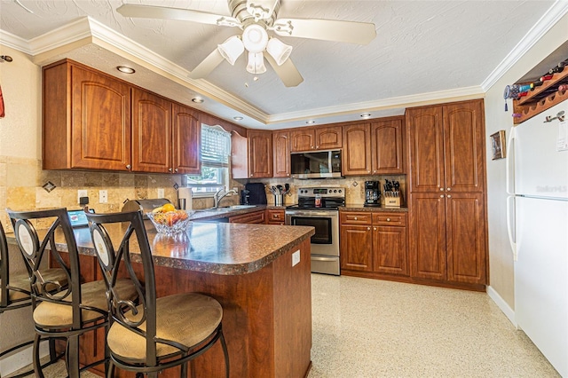 kitchen with a breakfast bar area, appliances with stainless steel finishes, tasteful backsplash, ornamental molding, and kitchen peninsula