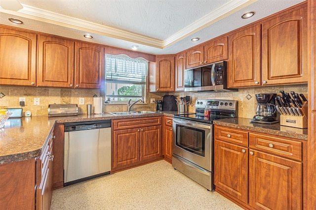 kitchen featuring sink, dark stone countertops, stainless steel appliances, decorative backsplash, and a raised ceiling