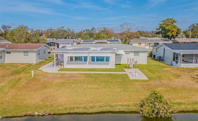 back of property featuring a yard, central AC, and a water view