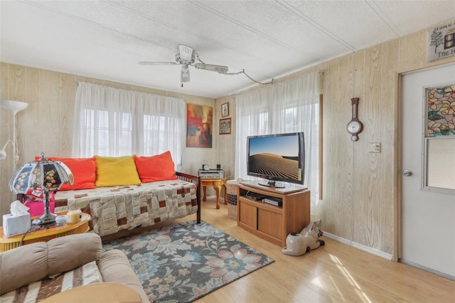 living room with wood-type flooring, wooden walls, and ceiling fan