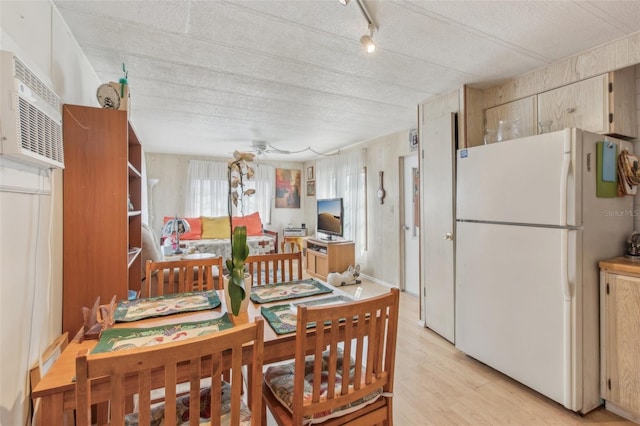 dining room with light hardwood / wood-style floors and a wall unit AC