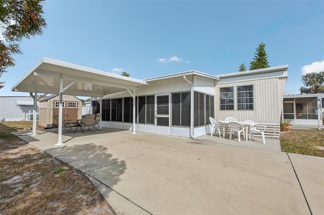 back of property with a patio, a storage unit, and a sunroom