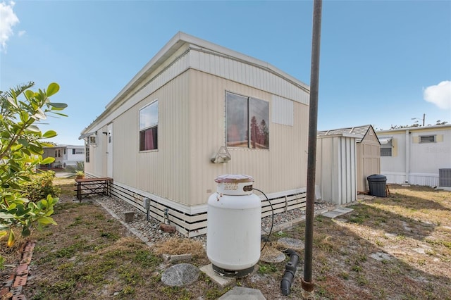 view of side of home featuring central AC unit and a shed