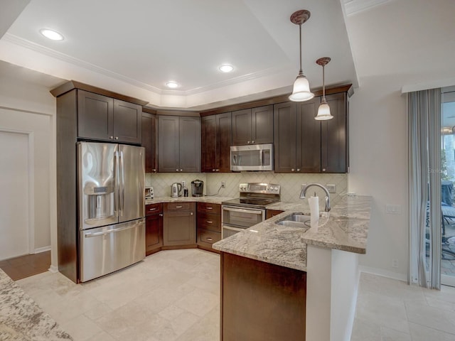 kitchen featuring appliances with stainless steel finishes, pendant lighting, sink, dark brown cabinetry, and light stone countertops