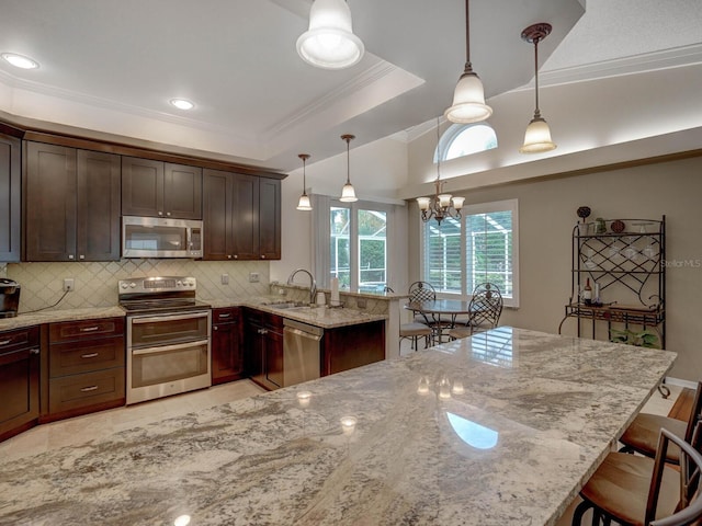 kitchen with appliances with stainless steel finishes, decorative light fixtures, backsplash, a kitchen breakfast bar, and light stone counters