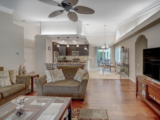 living room featuring ceiling fan with notable chandelier, ornamental molding, hardwood / wood-style floors, and a textured ceiling