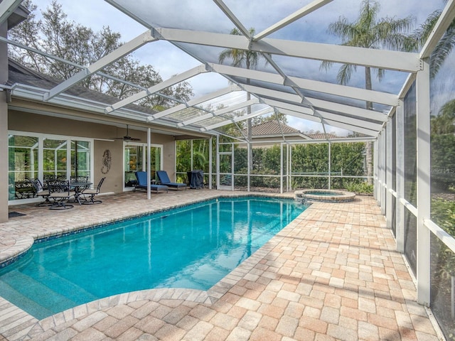 view of swimming pool featuring an in ground hot tub, ceiling fan, glass enclosure, and a patio