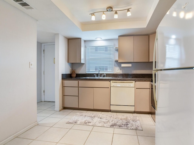 kitchen with sink, white appliances, light tile patterned flooring, a raised ceiling, and light brown cabinets