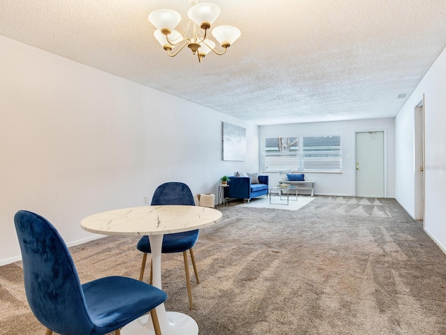 carpeted dining area with a chandelier and a textured ceiling