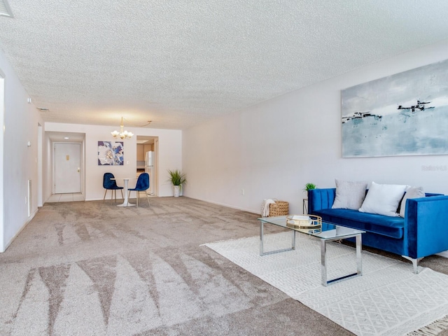 living room with a textured ceiling, a chandelier, and carpet flooring