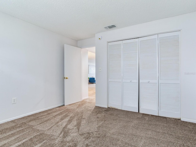 unfurnished bedroom with a closet, a textured ceiling, and carpet flooring