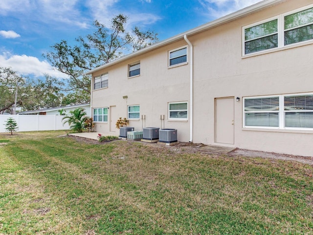 rear view of property featuring central AC and a lawn