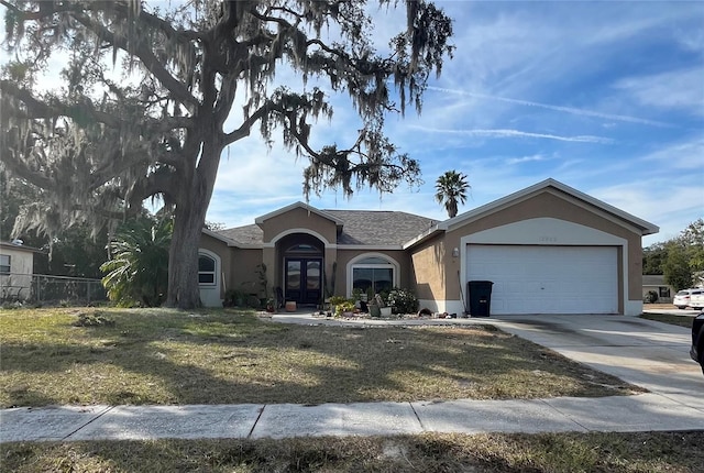 single story home with a garage, a front yard, and french doors