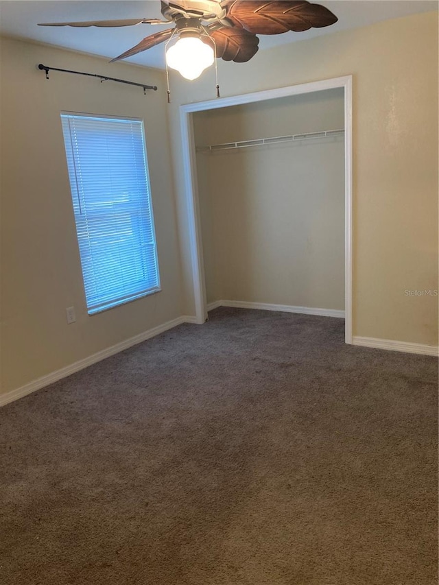 unfurnished bedroom with ceiling fan, a closet, and dark colored carpet