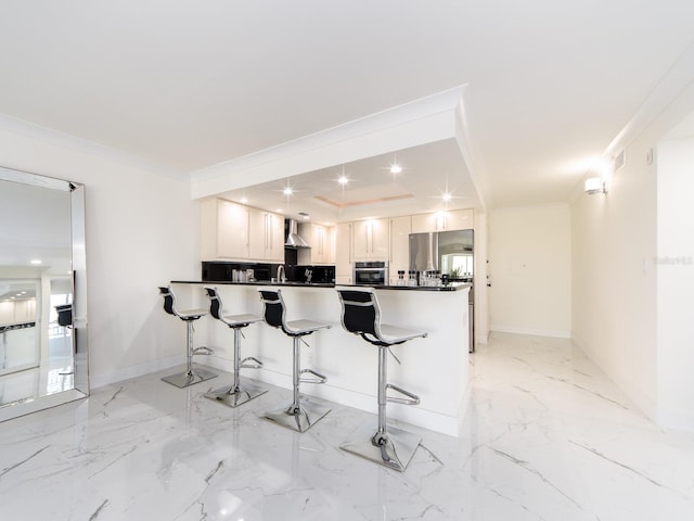 kitchen featuring crown molding, a breakfast bar, white cabinets, kitchen peninsula, and stainless steel oven