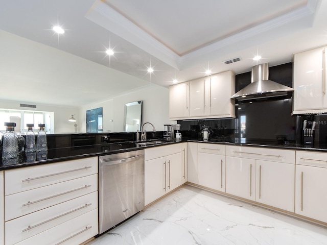 kitchen with wall chimney range hood, sink, white cabinets, stainless steel dishwasher, and a raised ceiling