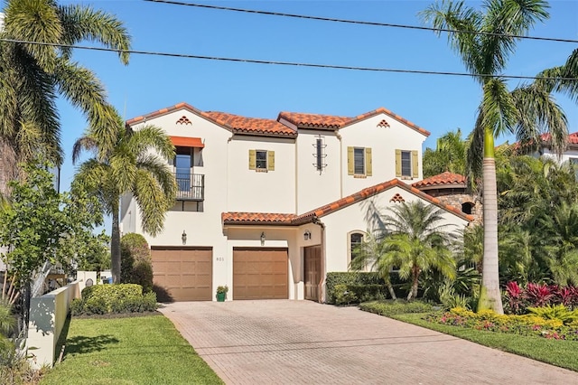 mediterranean / spanish home featuring a balcony, a tiled roof, decorative driveway, and stucco siding