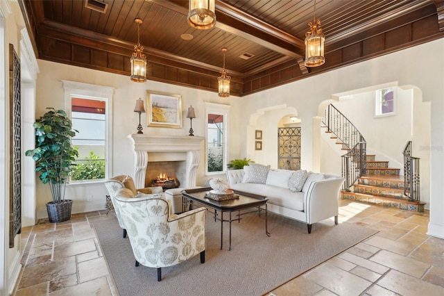 sitting room featuring wood ceiling, baseboards, stairs, a lit fireplace, and stone tile flooring