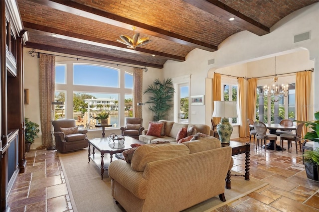 living area featuring brick ceiling, a high ceiling, a chandelier, and stone tile flooring