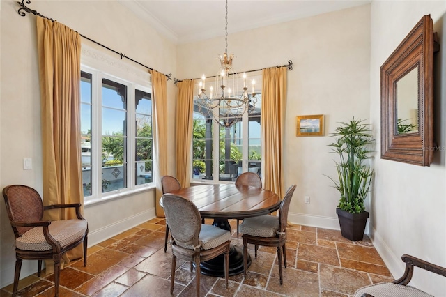 dining room with stone tile floors, baseboards, a chandelier, and ornamental molding