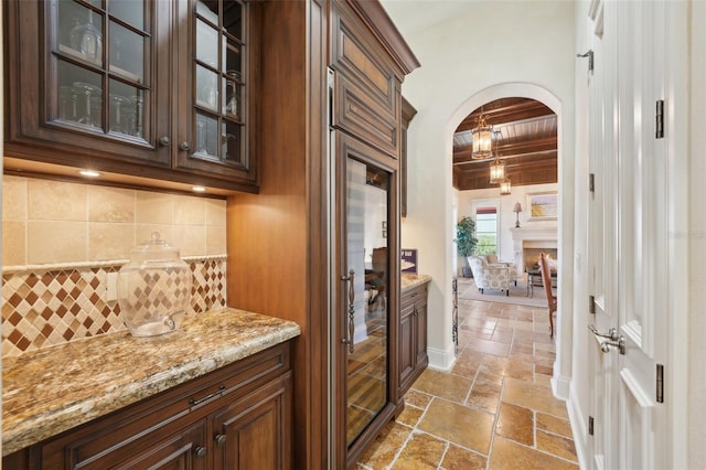 bar with stone tile floors, arched walkways, and decorative backsplash