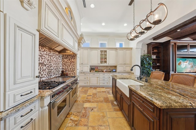 kitchen with range with two ovens, glass insert cabinets, decorative light fixtures, stone tile flooring, and a sink